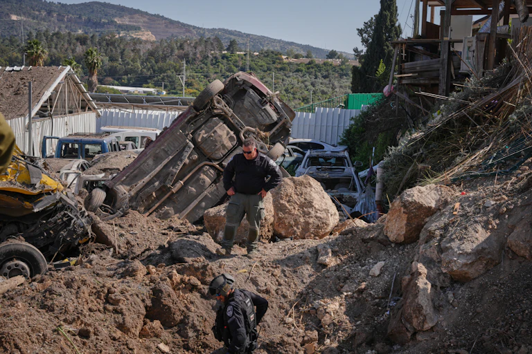 A man with his hands on his hips looks at rubble from an explosion.