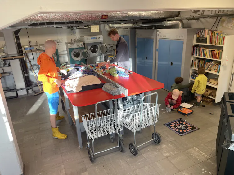 Two men folding the washing in the author's communal laundry area.