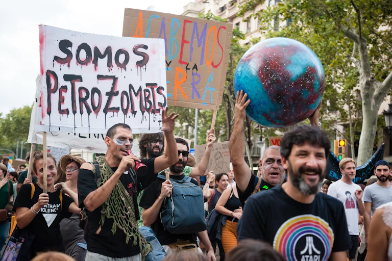 Manifestantes con pancartas y una bola del mundo