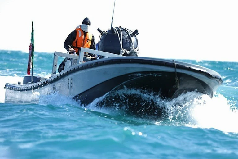 a person wearing a lifevest and facemask operates a speedboat carrying a large spherical object