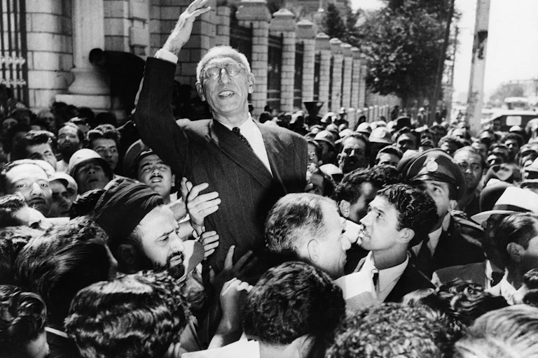 A man carried along by a crowd raises his arm in triumph.