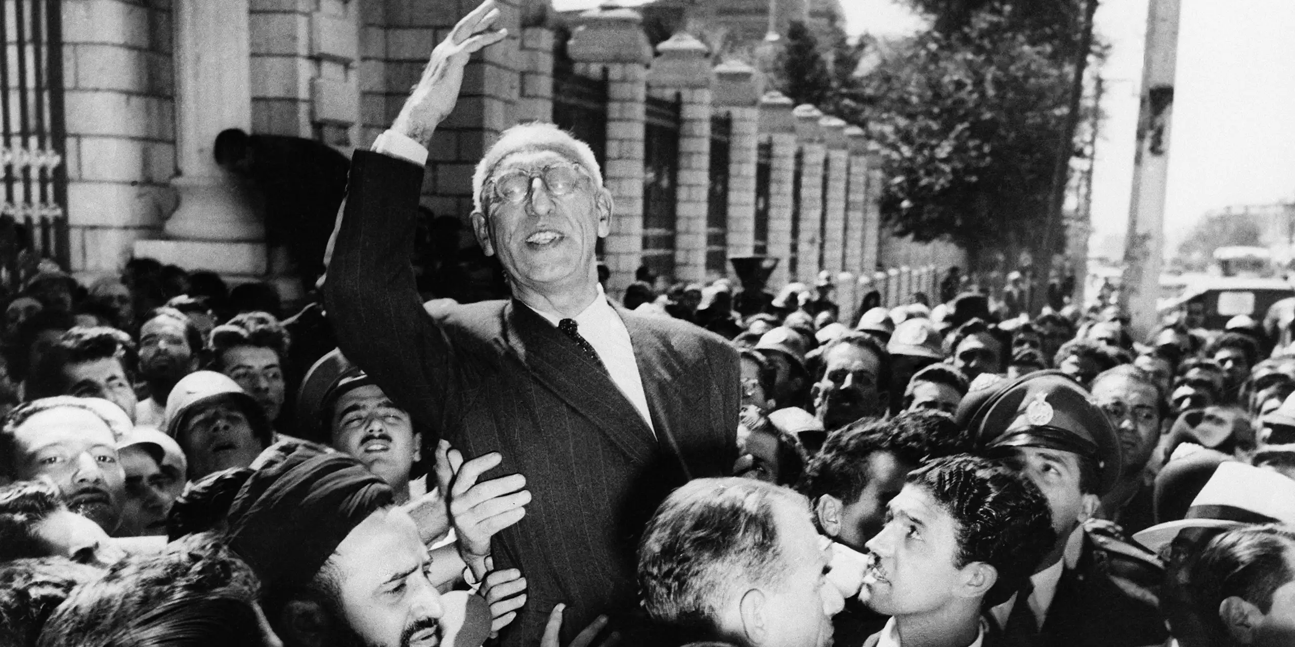 A man carried along by a crowd raises his arm in triumph.