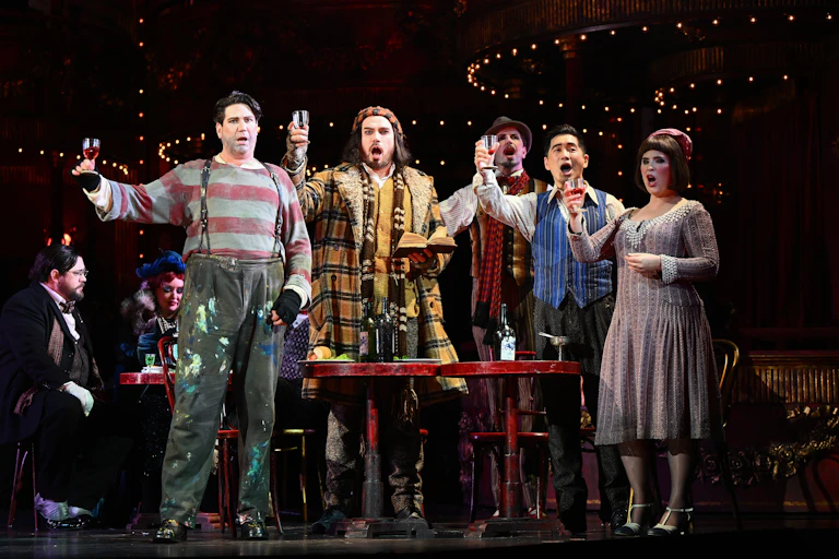 a performance of La Boheme, with actors in period dress singing and raising glasses
