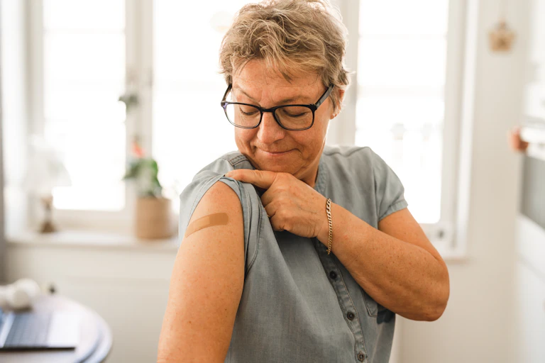 Woman looks at a bandaid on her arm after getting vaccinated