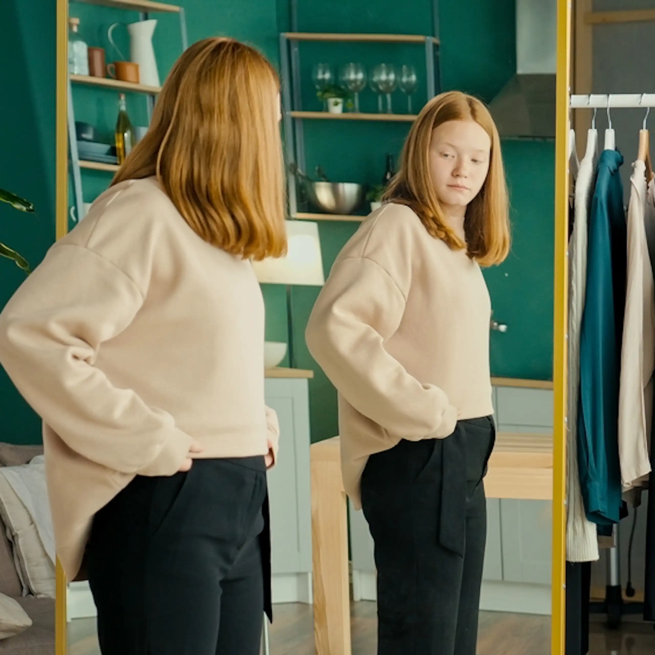Une jeune fille se regarde dans le miroir.