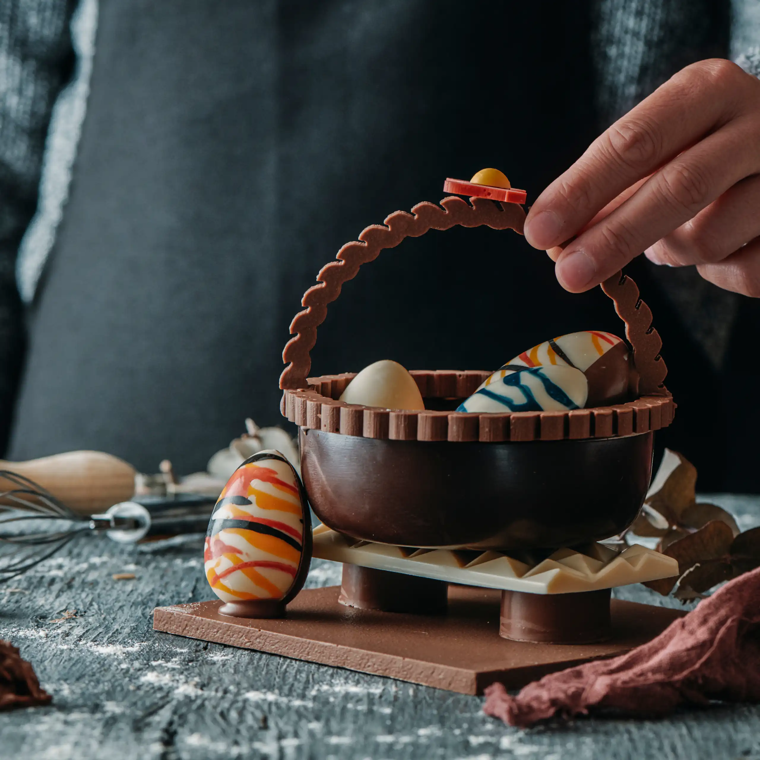 Una mona de Passqua de xocolata amb forma de cistella i ous dins.