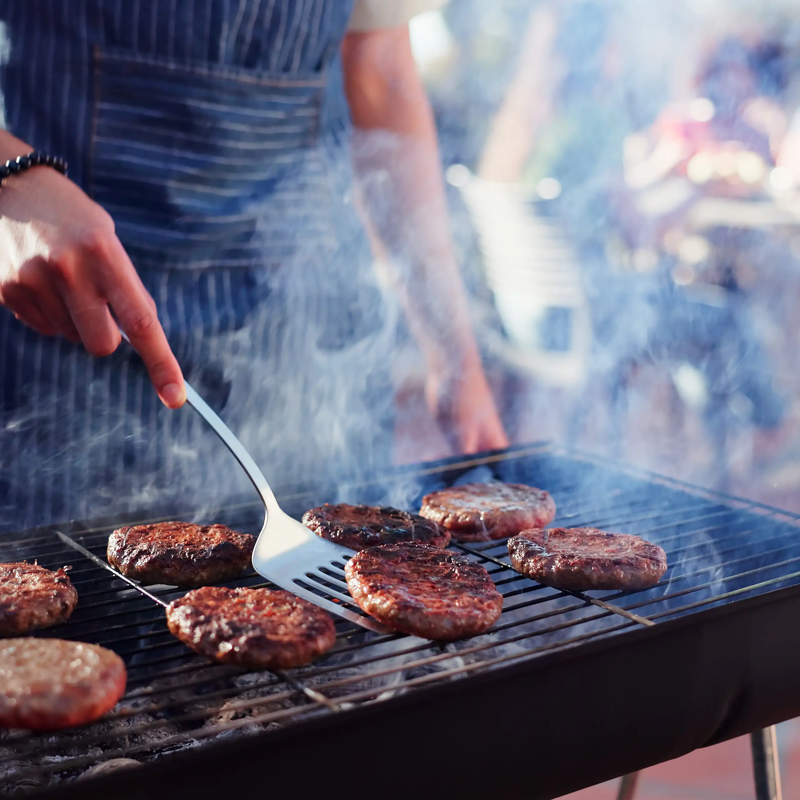 Una persona fent una barbacoa d'hamburgueses.