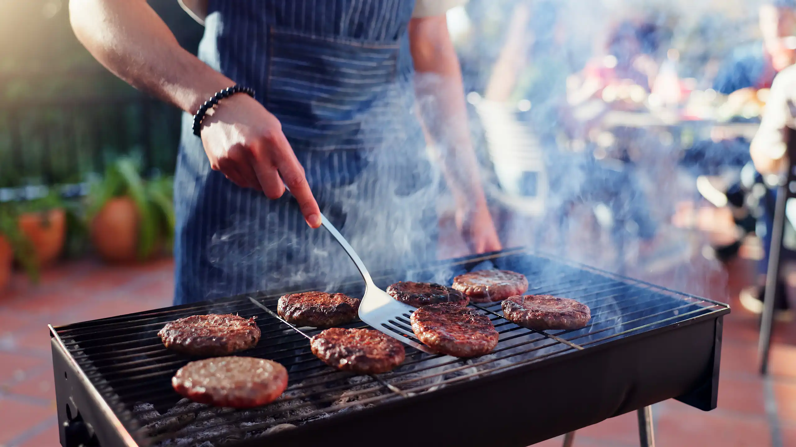 Una persona fent una barbacoa d'hamburgueses.