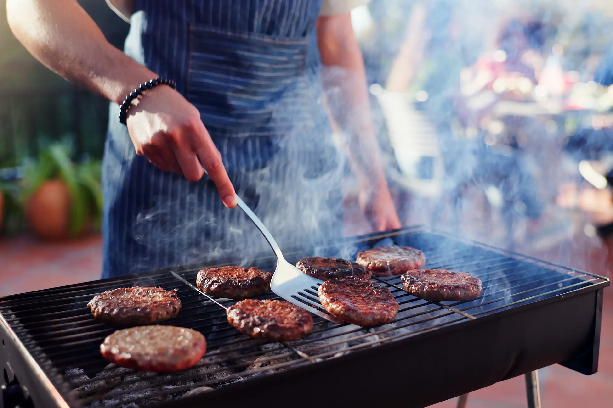 Una persona fent una barbacoa d'hamburgueses.