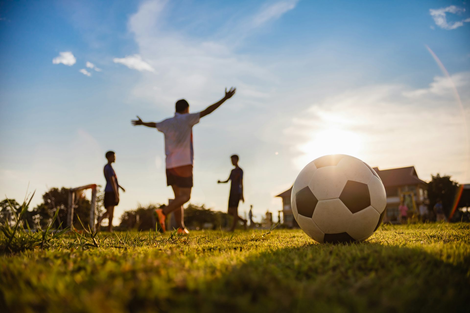 Photo focused on a football sitting on grass while players celebrate in the background