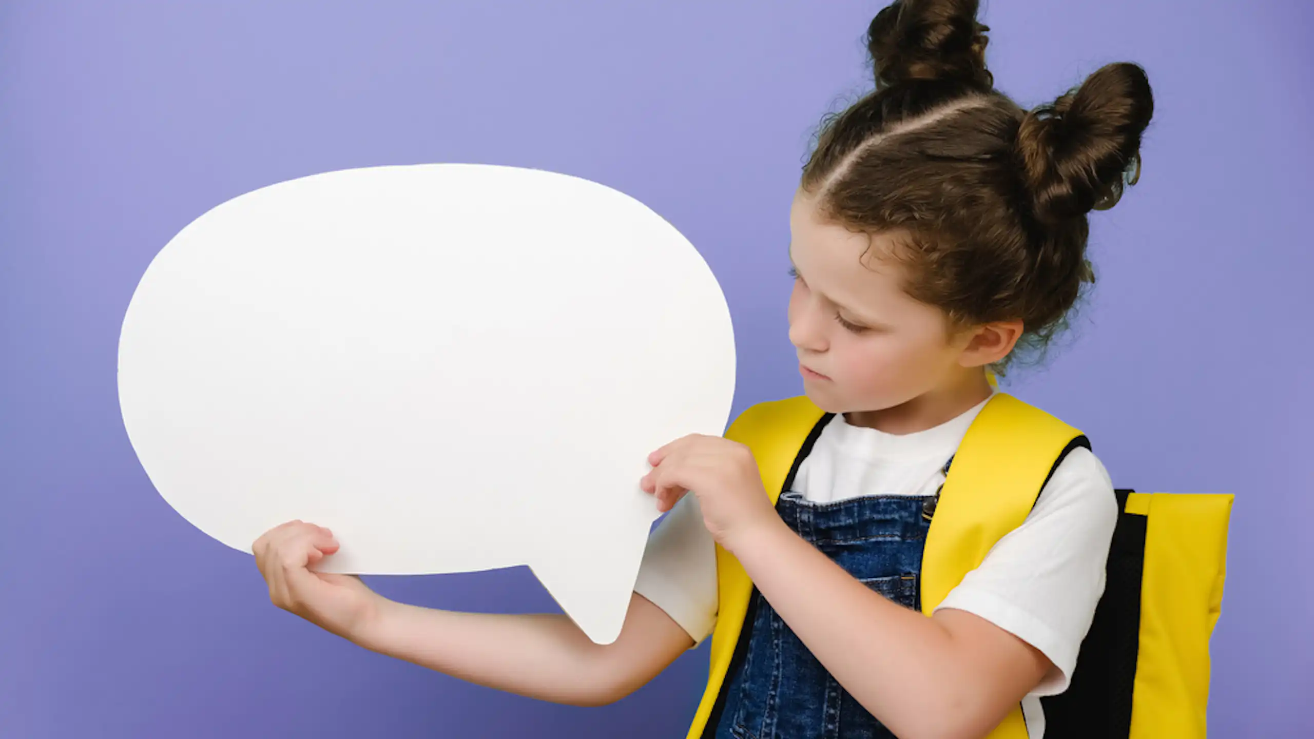 Une petite fille avec un cartable tenant une bulle.