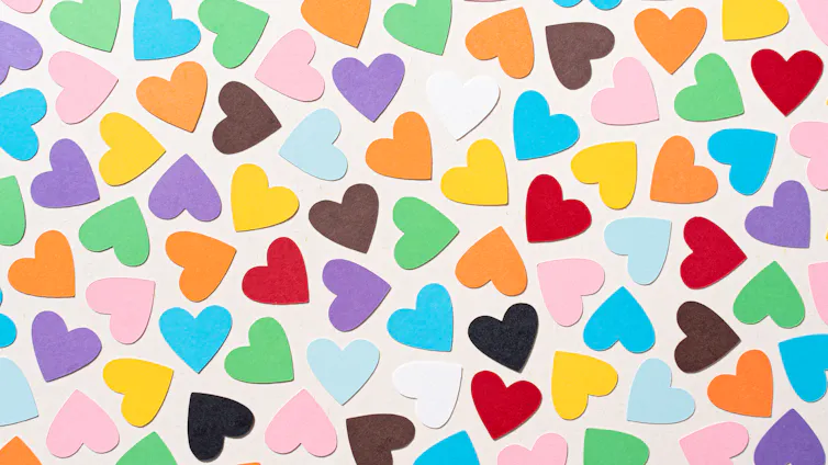 Corazones multicolores están dispersos sobre un fondo blanco.
