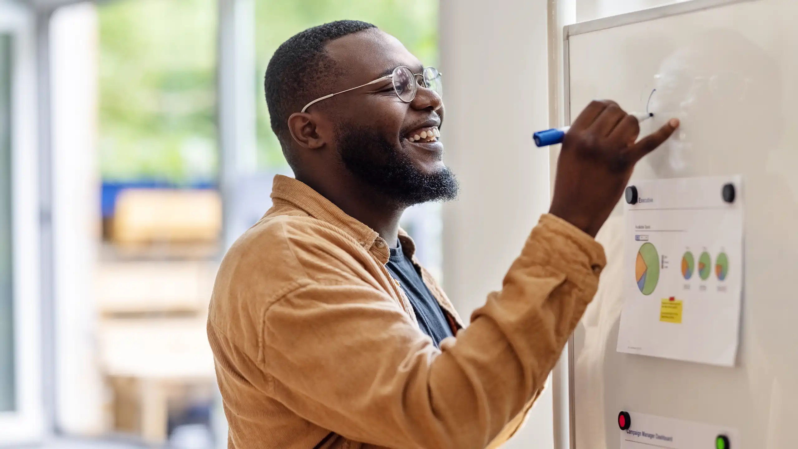 Smiling man writing on a whiteboard.