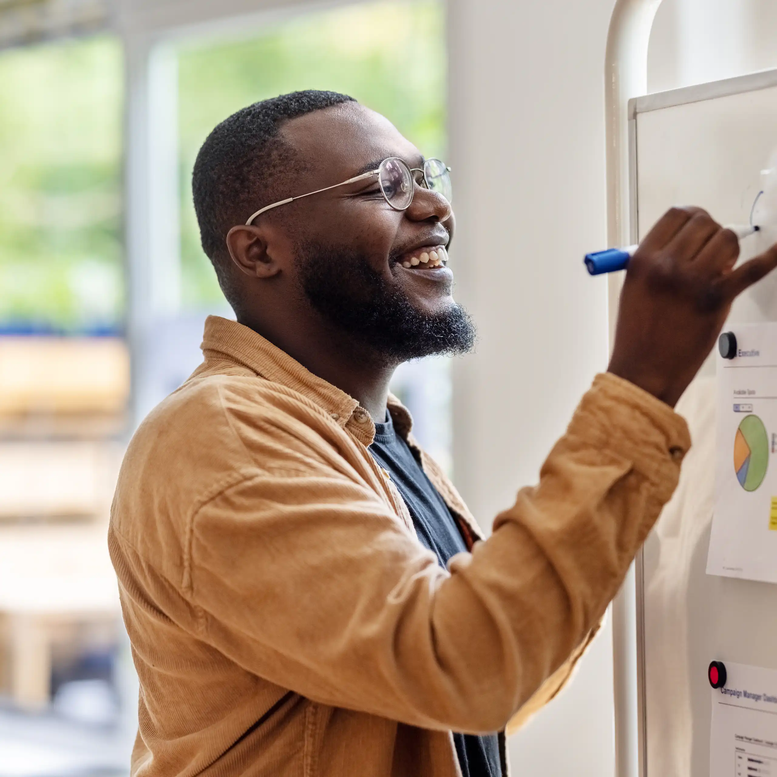 Smiling man writing on a whiteboard.