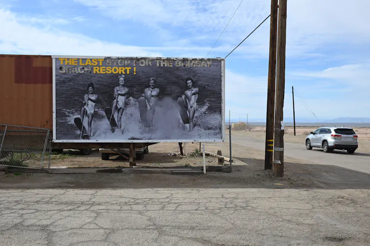 A billboard on a dusty, empty highway.