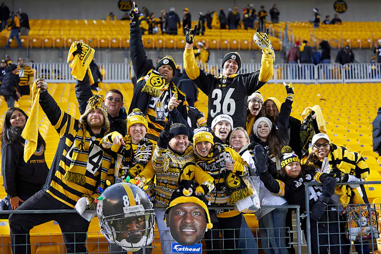 A group of people wearing black-and-gold football jerseys and apparel.
