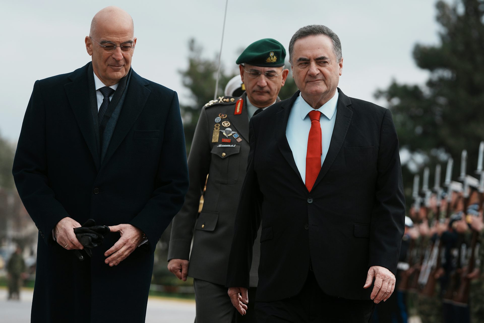 Dos hombres con abrigos pasan junto a una fila de soldados.