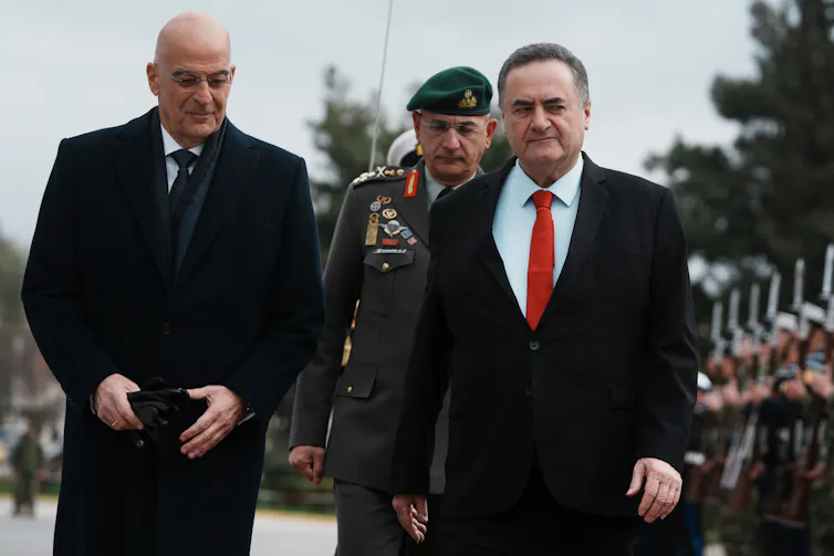 Israel no sólo está respondiendo a las amenazas: está remodelando Oriente Medio 1 Dos hombres con abrigos pasan junto a una fila de soldados.