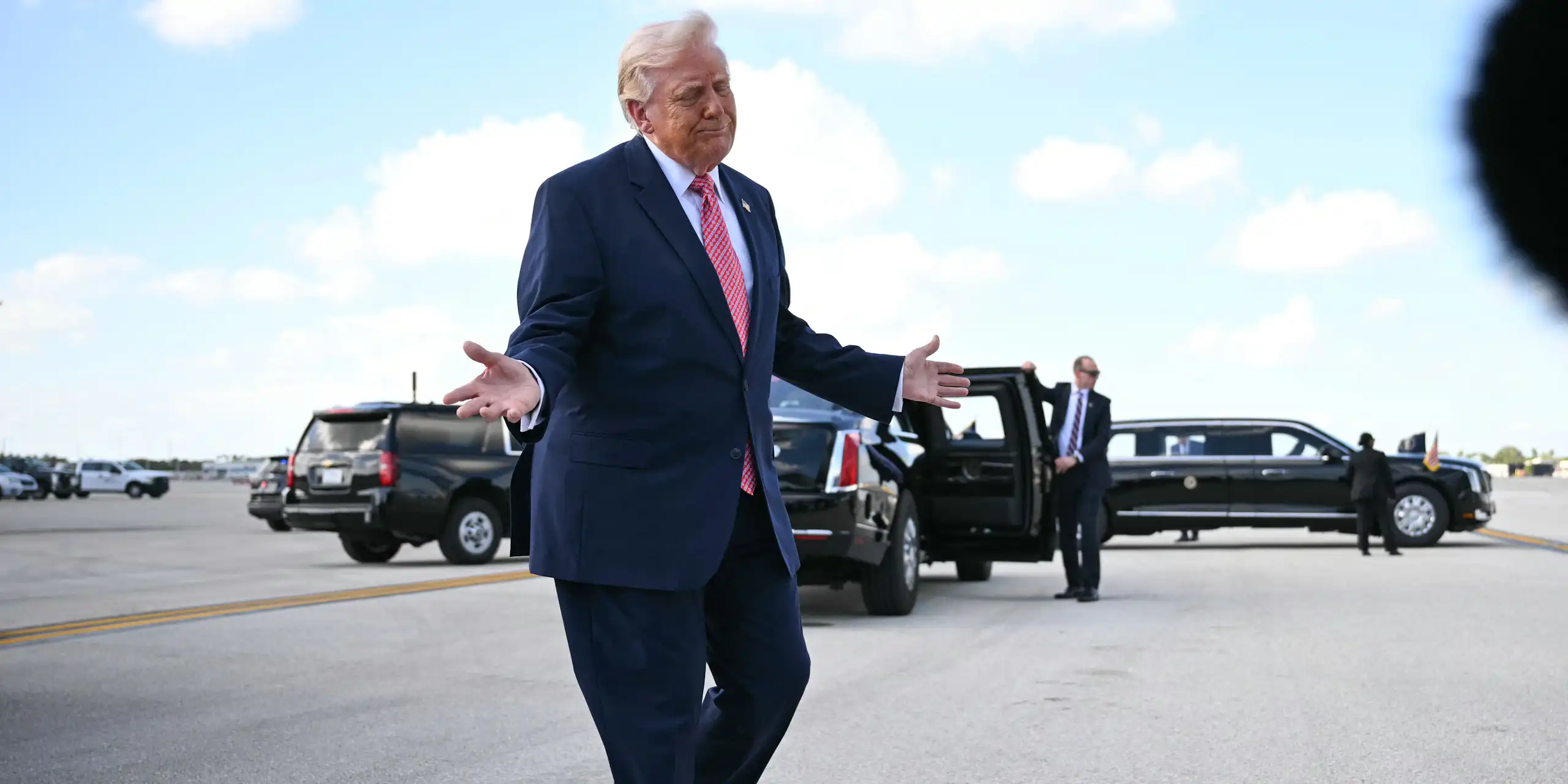 A man in a suit gesticulates with his hands
