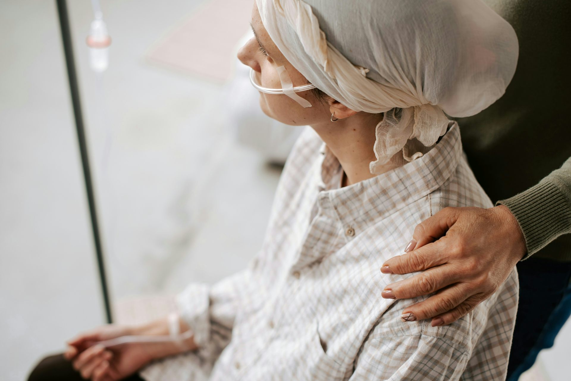 Une personne sous intraveineuse est assise tandis qu’une proche la tient par l’épaule