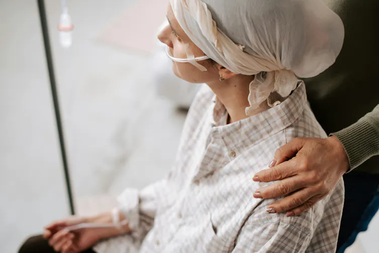 Une personne sous intraveineuse est assise tandis qu’une proche la tient par l’épaule