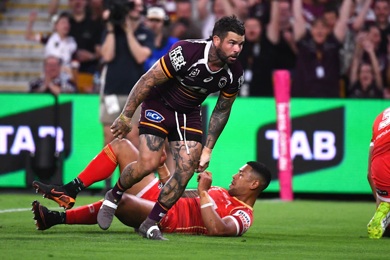 Adam Reynolds of the Broncos scores a try against the Dolphins, with TAB signage showing on the sidelines.