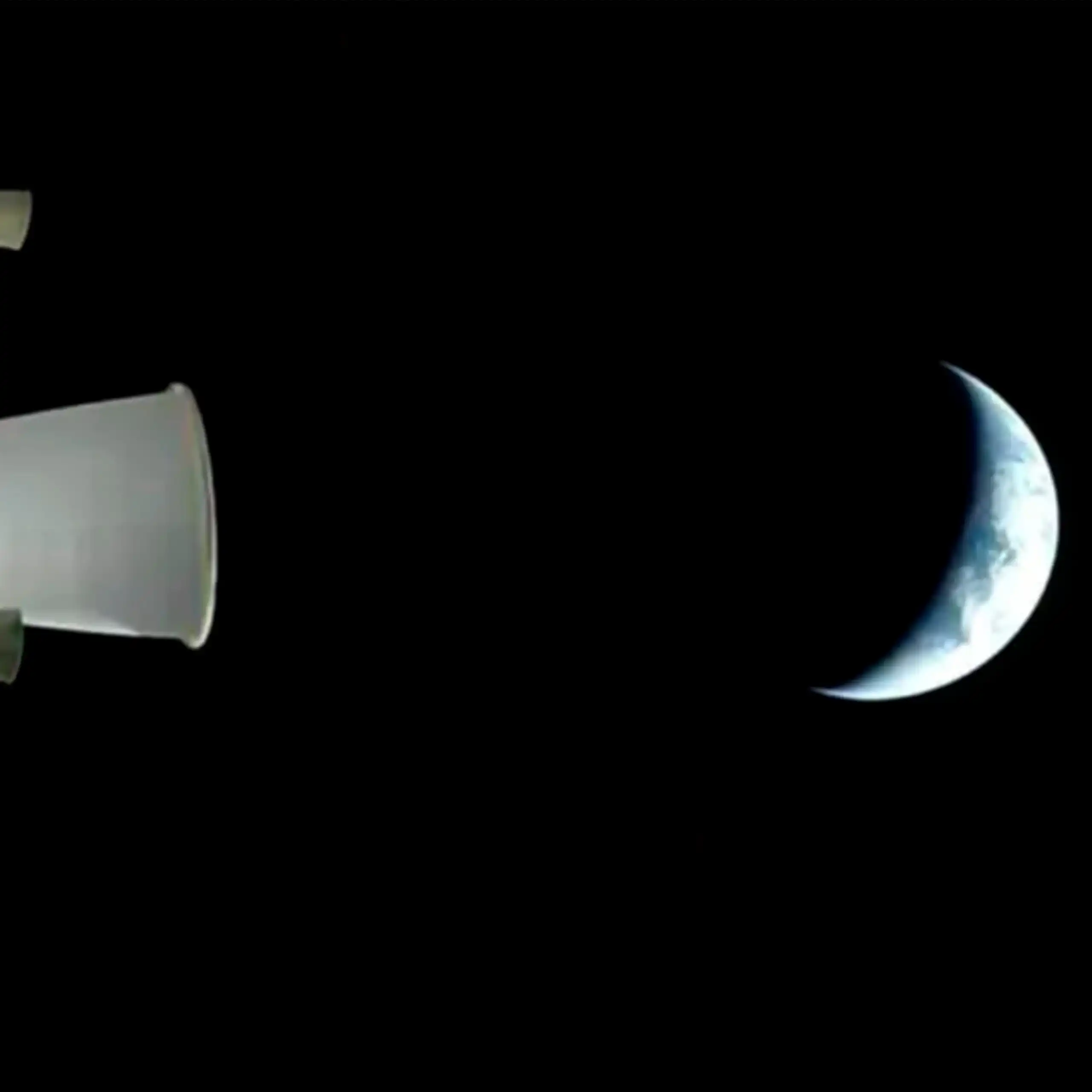 The Earth seen from a distance in space. Only a crescent of it is visisble; the rest is in shadow