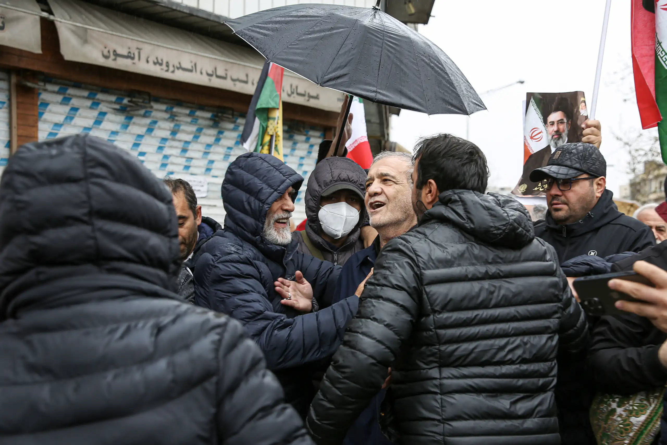 A man stands under an umbrella.