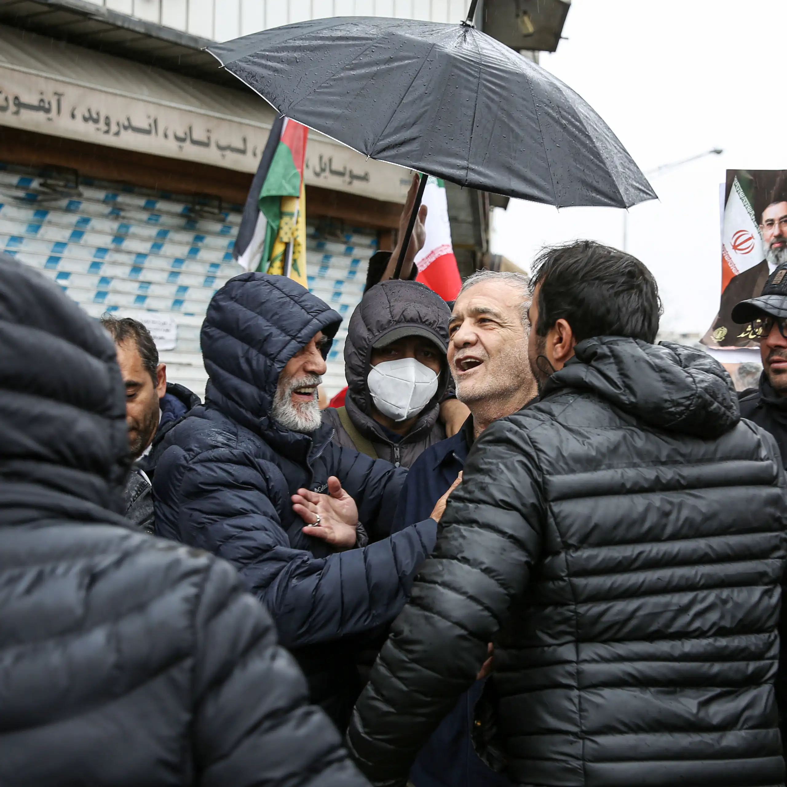 A man stands under an umbrella.