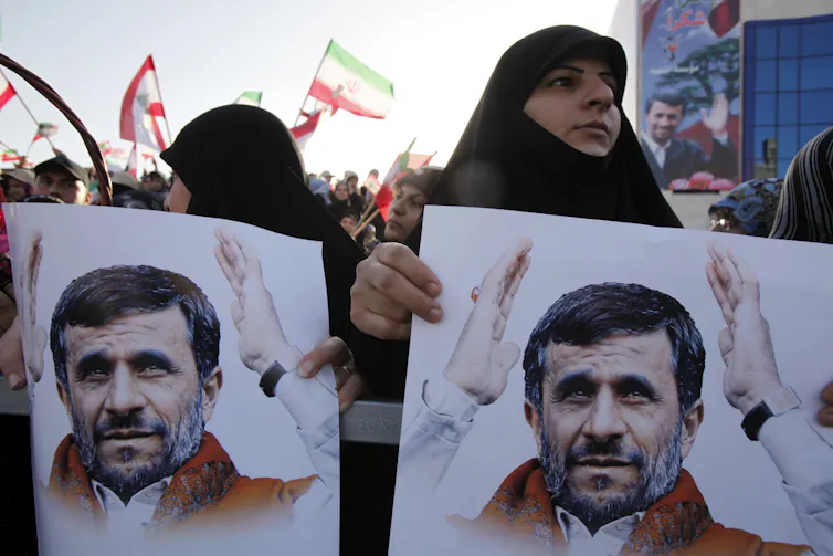 El presidente de Irán atrae a los estadounidenses, pero ¿su oficina todavía tiene poder real? 2 Dos mujeres sostienen carteles con la imagen de un hombre.