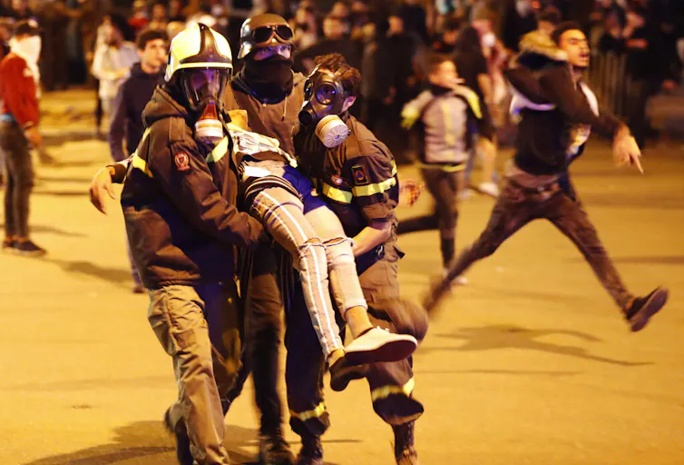 Two people carry an injured man at a protest.