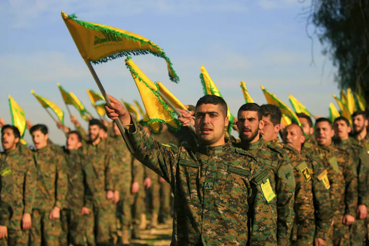 Men in military fatigues hold flags.