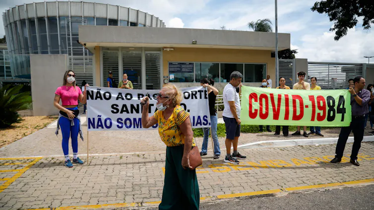 Pessoas seguram cartazes durante um protesto contra os passaportes de vacinação contra a COVID-19 e a vacinação obrigatória contra a COVID-19 no Brasil.