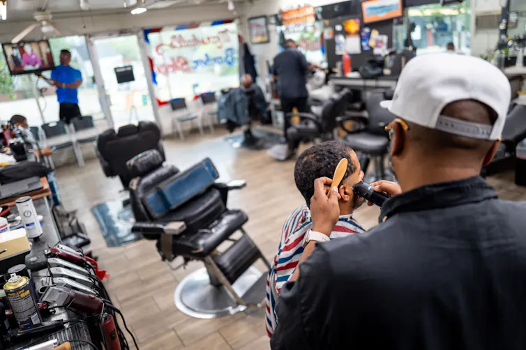 Un barbero le corta el pelo a un hombre.