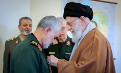 Un hombre se coloca la medalla de otro en la solapa.