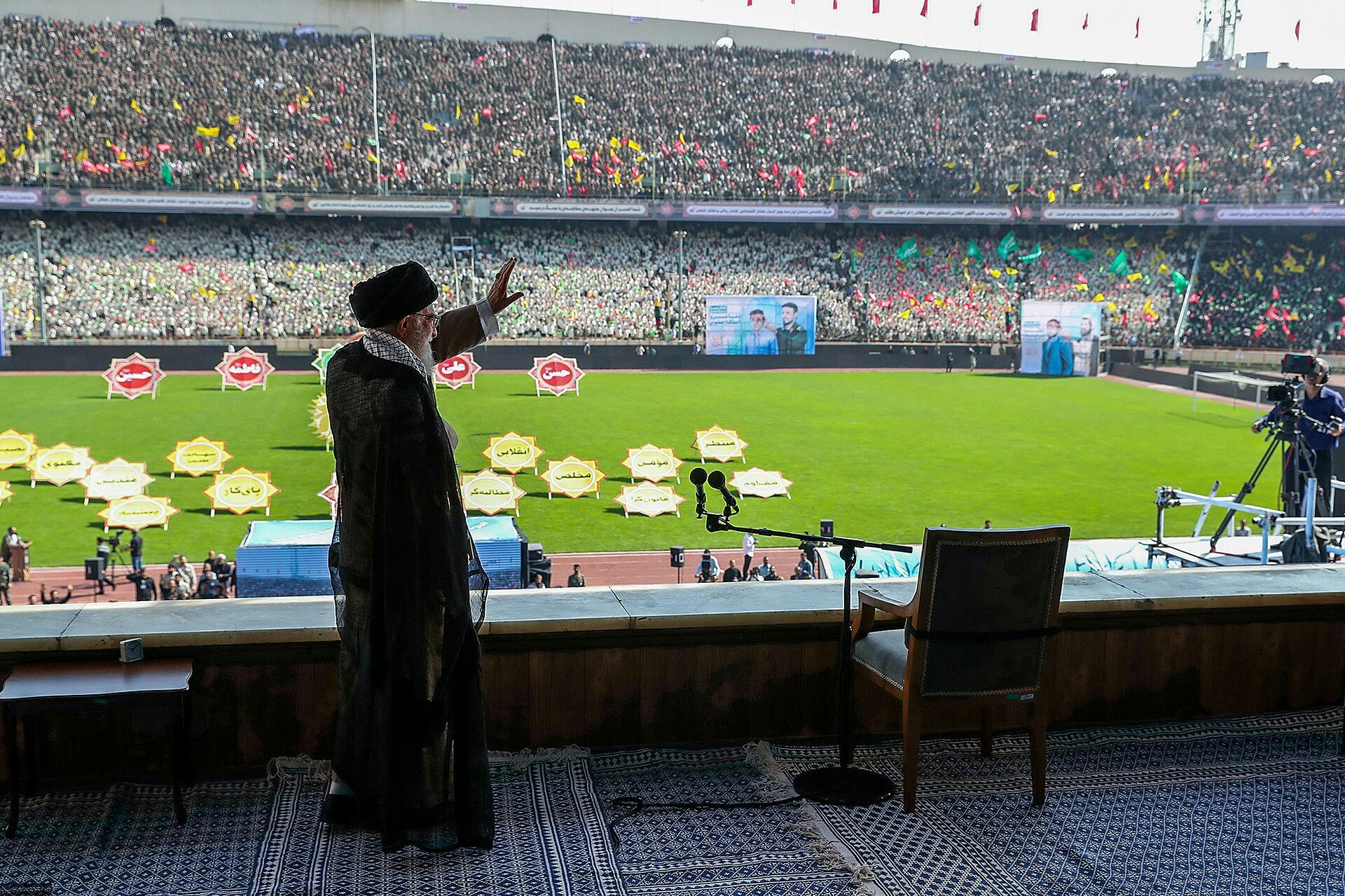 Un hombre saluda a una gran multitud en un estadio de atletismo.