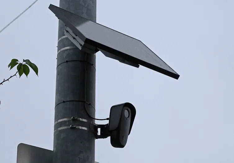 A camera and solar panel attached to a traffic pole