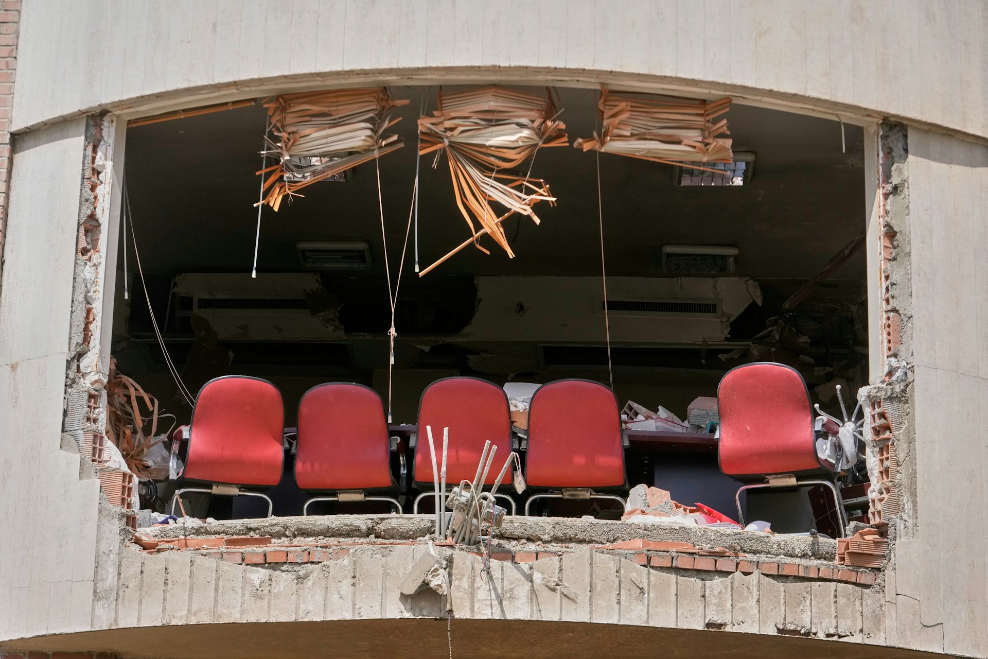 A row of red chairs in a destroyed university building.