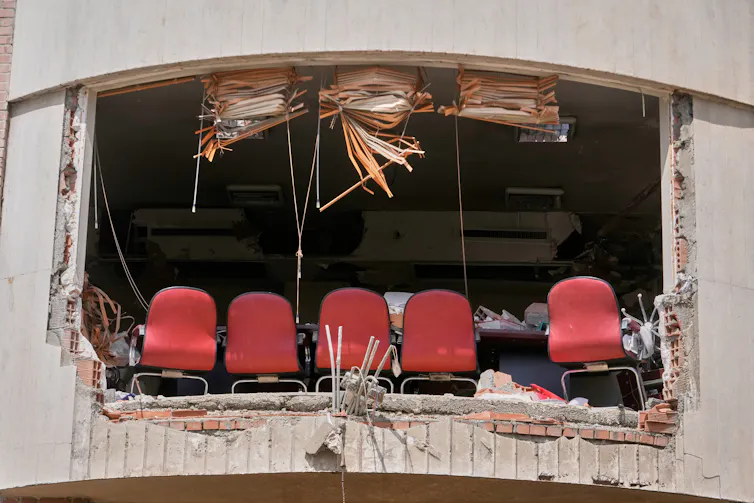 A row of red chairs in a destroyed university building.