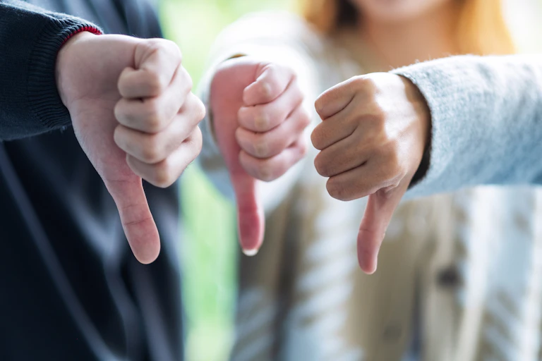 A group of people making thumbs-down hands sign.