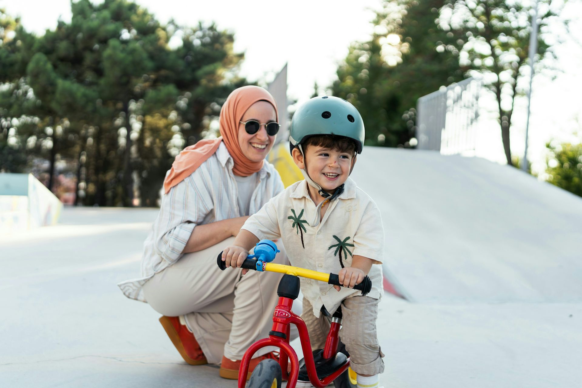 Un niño en una bicicleta estática con un padre sonriente detrás de él.