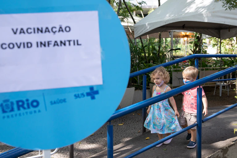 Two children leave a COVID-19 vaccination site in Rio De Janeiro after receiving a vaccine.