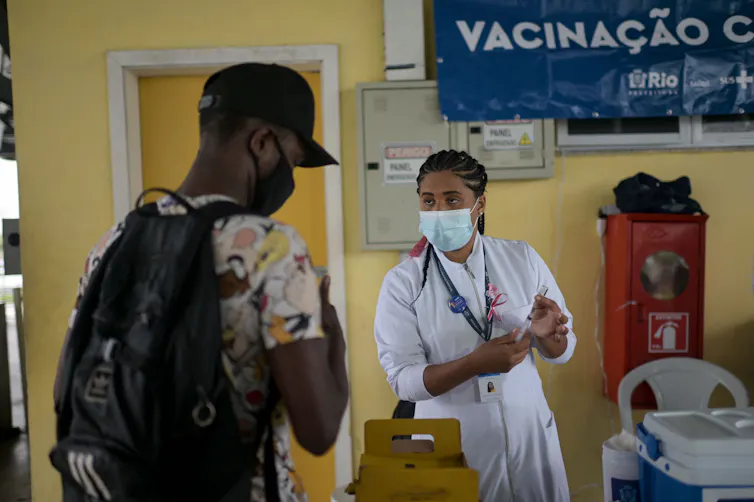 Um passageiro usando máscara recebe a vacina contra a COVID-19 em uma rodoviária do Rio de Janeiro.
