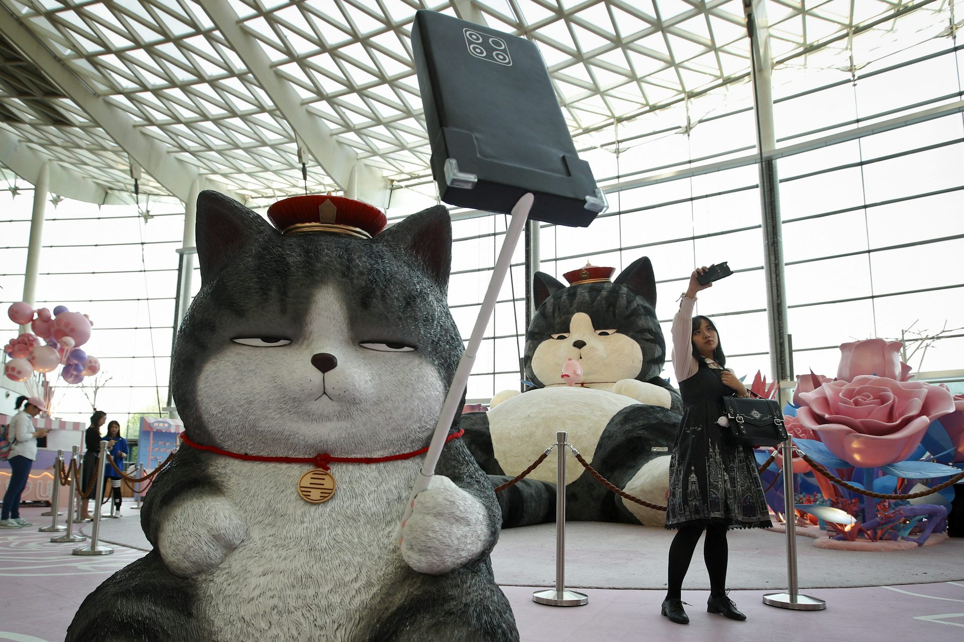 A woman takes a selfie near a statue of a large cat.   