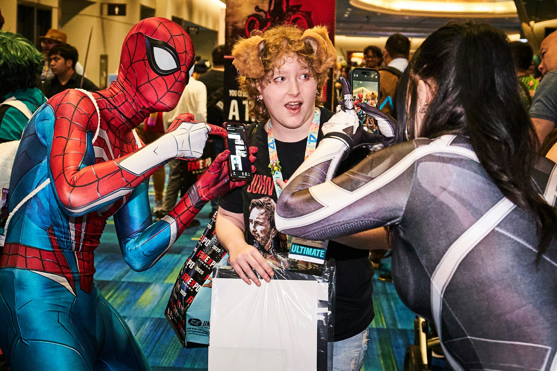 Una persona disfrazada de Spider-Man se besa con otra mientras alguien toma una foto con su teléfono.