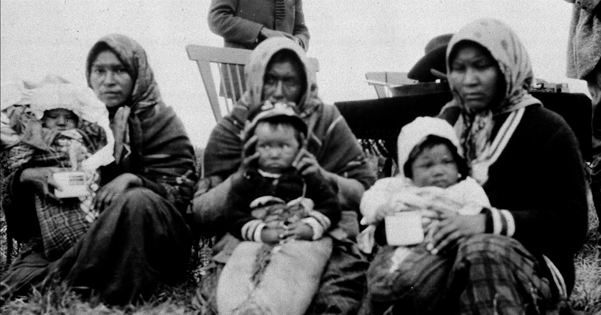 Fotografía en blanco y negro que muestra a mujeres indígenas sosteniendo a sus bebés.