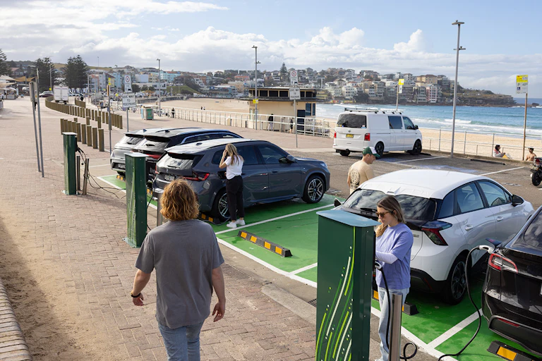 woman charging her electric car while parked at beach.