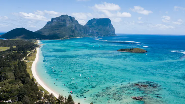 A coral reef lagoon with a large rocky mountain in the background.