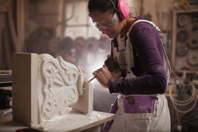 A stonemason using tools to shape an elaborate column.