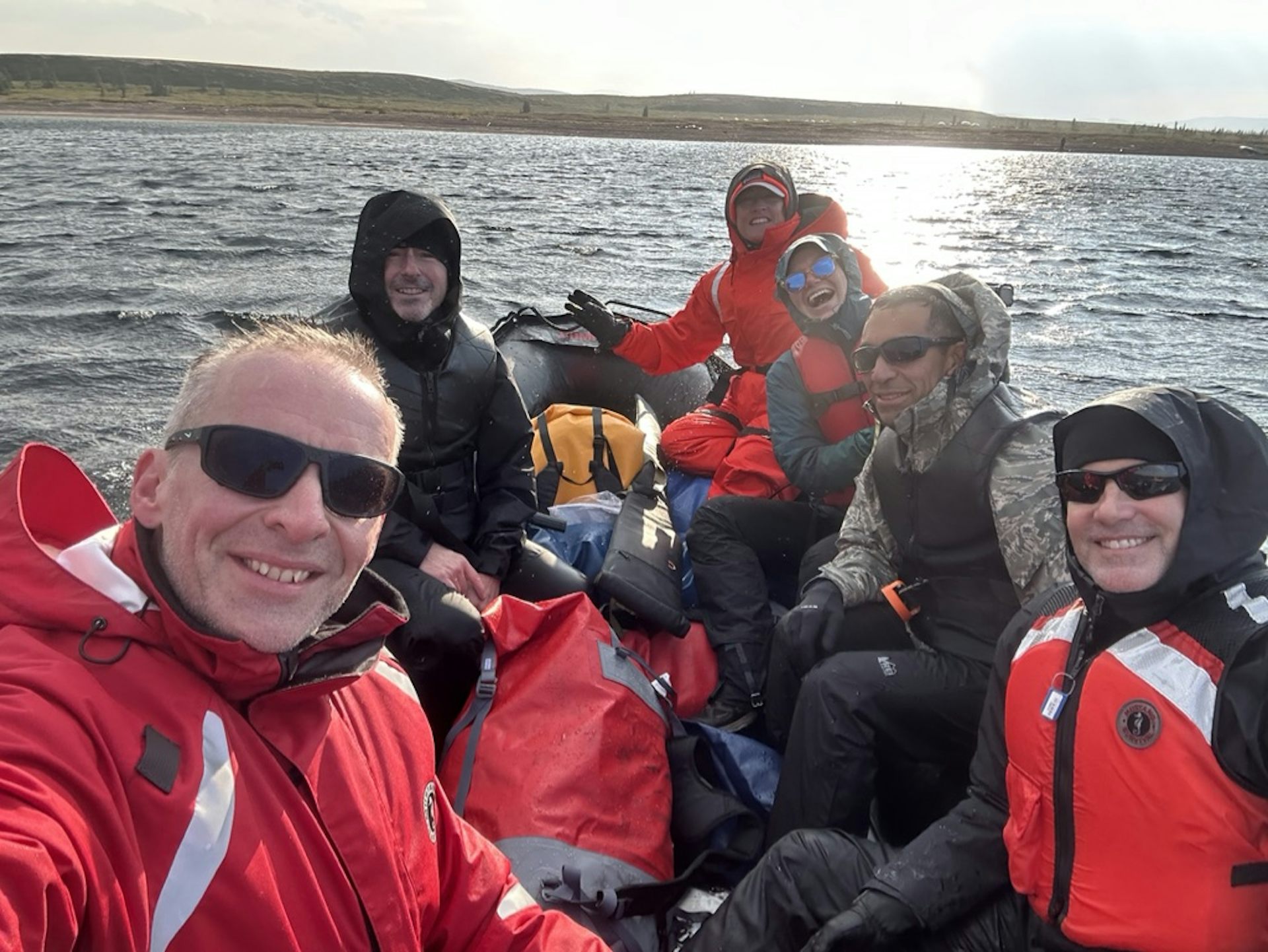 The team wearing red jackets in a zodiac boat on the ocean.